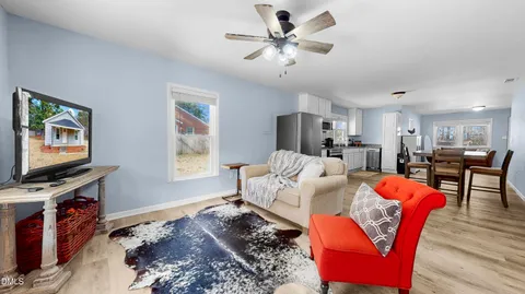 a living room with furniture a flat screen tv and kitchen view
