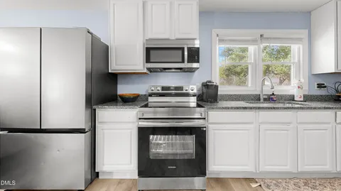 a kitchen with granite countertop a refrigerator stove and microwave