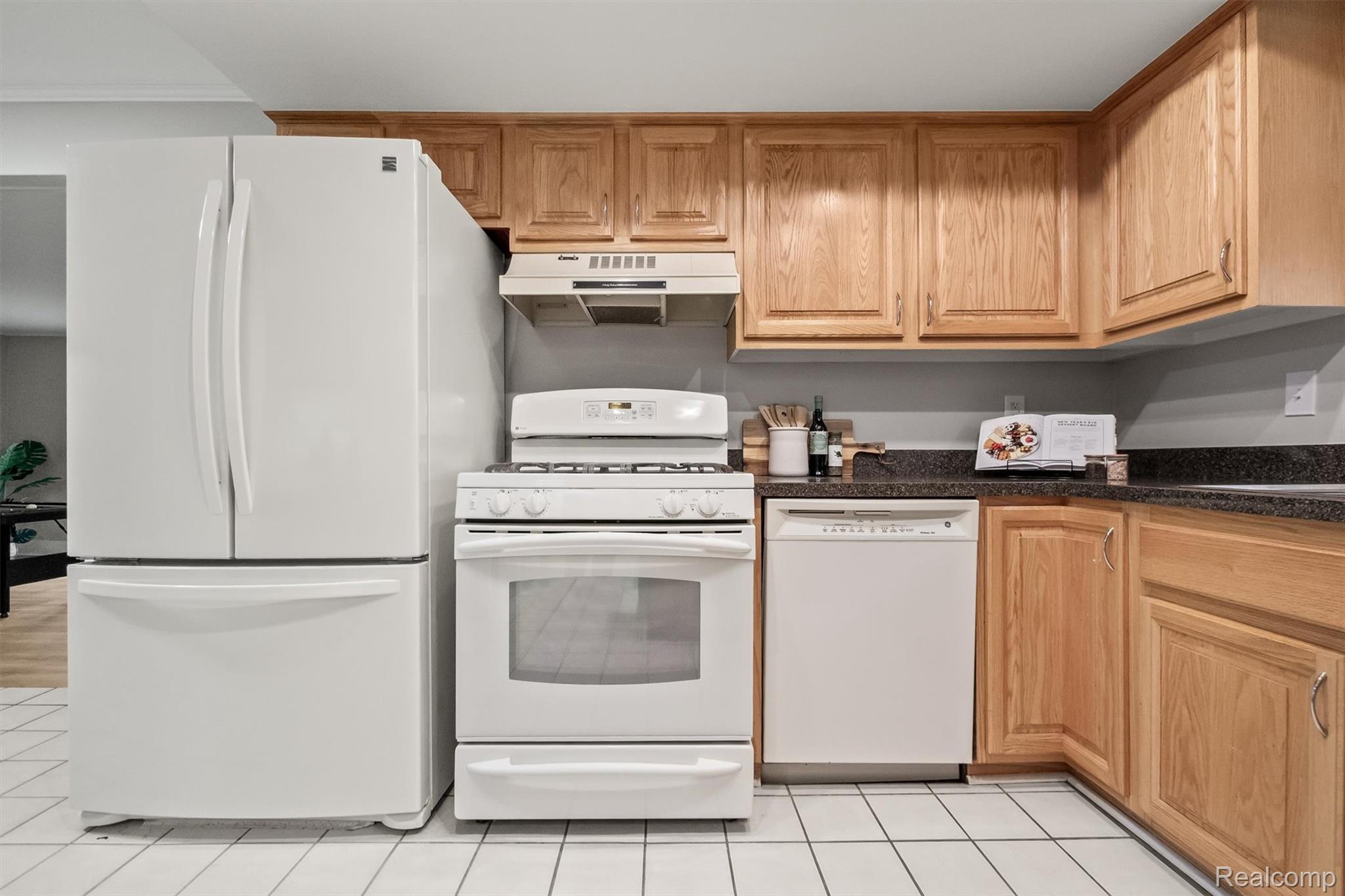 11326 Common Road Warren, MI 48093 - Photo 18 of 35 Kitchen with white appliances, dark stone counters, light tile patterned flooring, and light wood finish cabinetry