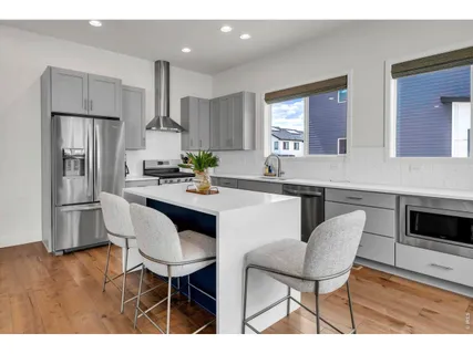 a kitchen with stainless steel appliances a dining table chairs and a refrigerator