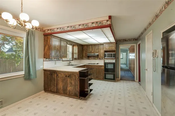 a kitchen with stainless steel appliances granite countertop a refrigerator a sink dishwasher a stove and a dining table with wooden floor