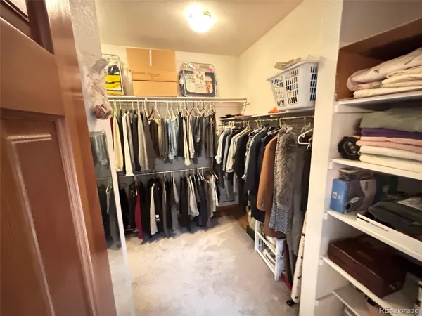 a view of walk in closet with clothes and shoes