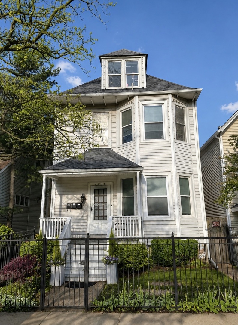 3749 North Seminary Avenue, Unit 1 Chicago, IL 60613 - Photo 1 of 25 a view of a white house with large windows and a small yard