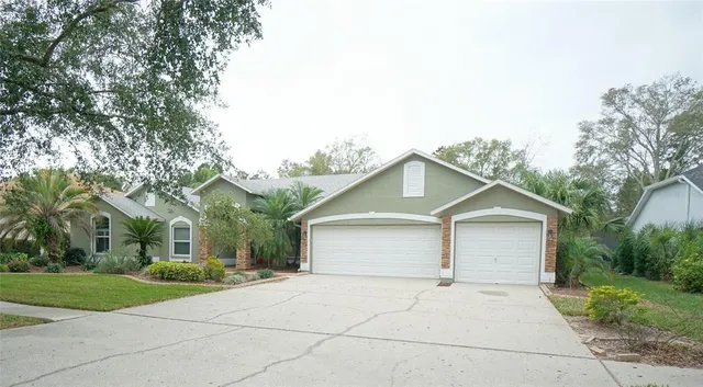 front view of house with a yard and trees all around