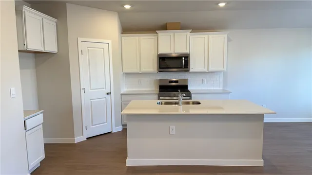 a view of kitchen with stainless steel appliances granite countertop a sink a stove and a refrigerator