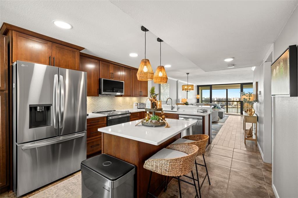 9525 Blind Pass Road, Unit 507 St. Pete Beach, FL 33706 - Photo 3 of 53 a kitchen with a refrigerator a dining table and chairs