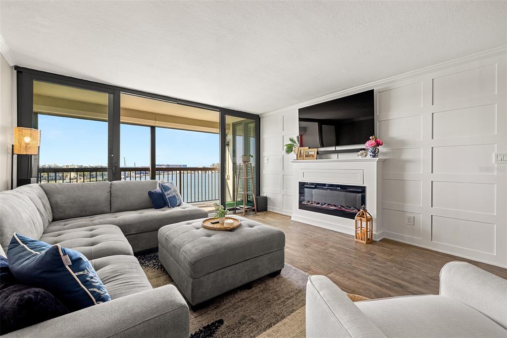 9525 Blind Pass Road, Unit 507 St. Pete Beach, FL 33706 - Photo 4 of 53 a living room with furniture a fireplace a flat screen tv and a large window