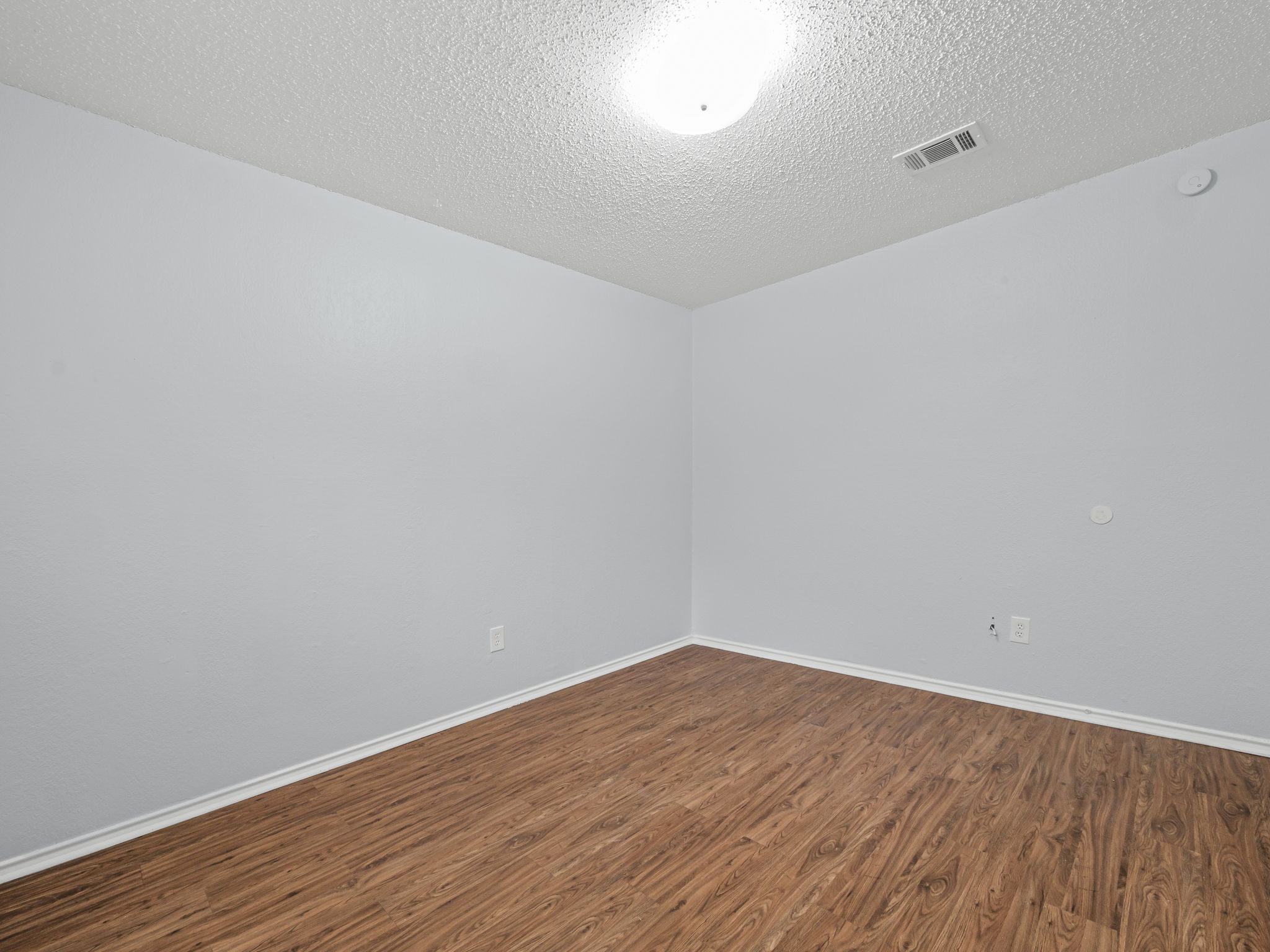 1816 Rawhide Loop, Unit 1822 Round Rock, TX 78681 - Photo 15 of 17 Unfurnished room with dark wood finished floors, a textured ceiling, and a smoke detector