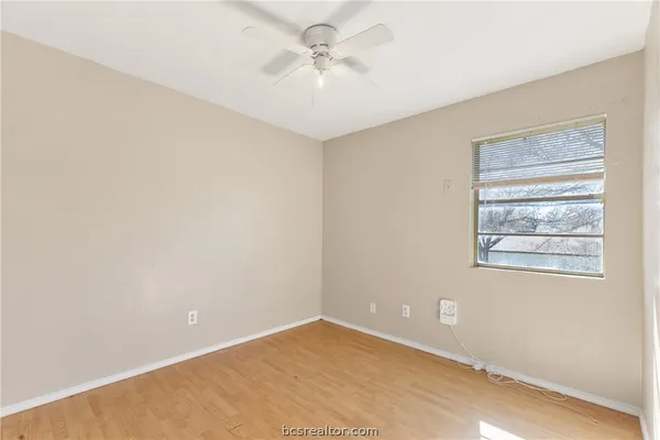 an empty room with windows and fan