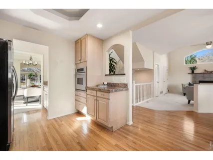 a open kitchen with granite countertop a stove top oven a sink dishwasher and white cabinets with wooden floor