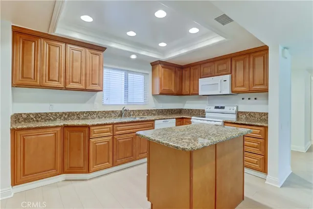 a kitchen with kitchen island granite countertop wooden cabinets a sink and dishwasher