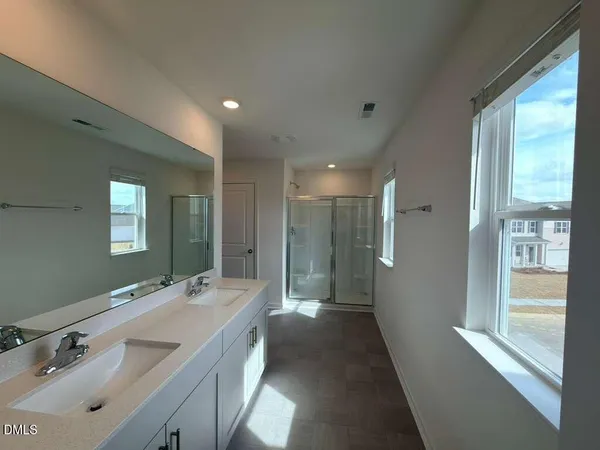 a spacious bathroom with a double vanity sink a mirror and a shower