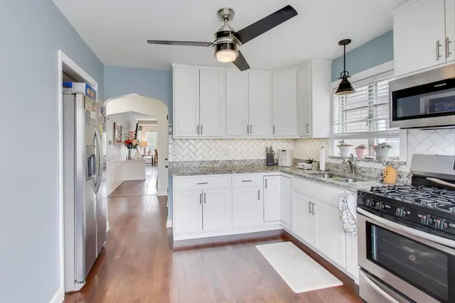 a kitchen with stainless steel appliances a stove a sink and white cabinets