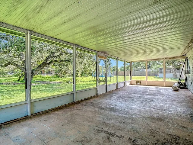 a view of an empty room with wooden deck and a yard