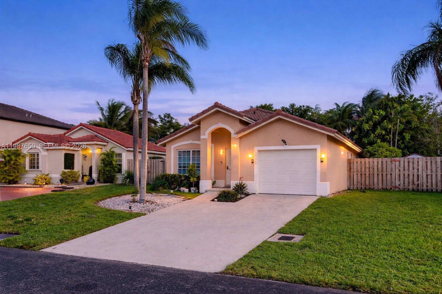 8858 Southwest 214th Street Cutler Bay, FL 33189 - Photo 3 of 41 a front view of a house with a yard and garage