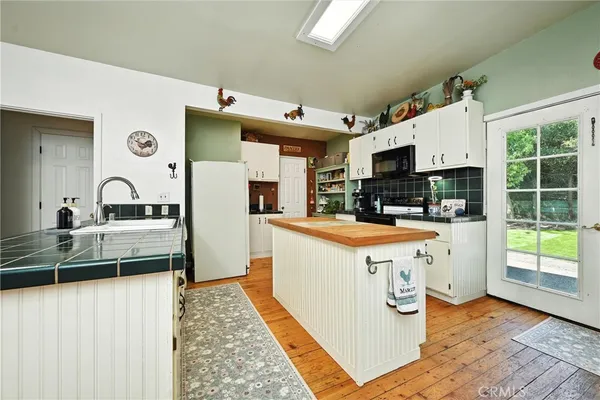 a kitchen with stainless steel appliances granite countertop a stove a sink dishwasher and a refrigerator with wooden floor