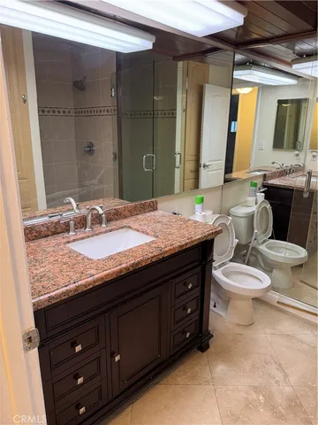 a bathroom with a granite countertop toilet sink and mirror