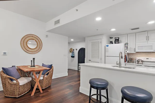 a living room with stainless steel appliances furniture a clock and a window