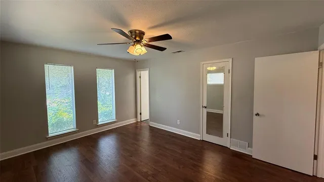a view of an empty room with a window and wooden floor