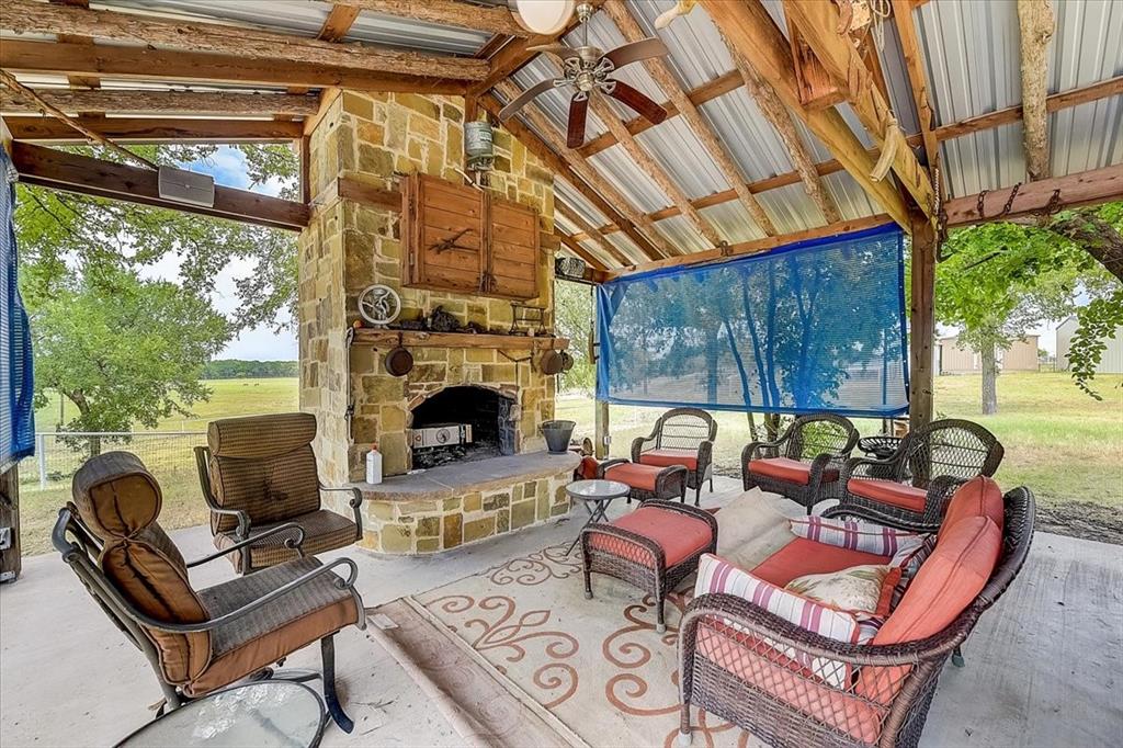9494 Waide Road Sanger, TX 76266 - Photo 19 of 40 View of outdoor living area with ceiling fan and an outdoor stone fireplace. There is also a full kitchen outdoors overlooking pool.