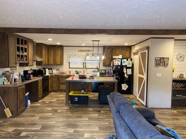 a kitchen with stainless steel appliances kitchen island granite countertop a refrigerator a stove top oven and a sink with island