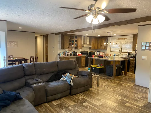 a living room with furniture kitchen view and a chandelier