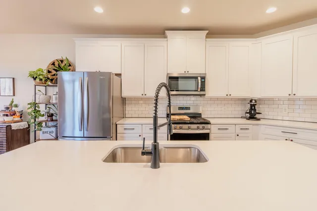 a kitchen with stainless steel appliances a refrigerator sink and microwave