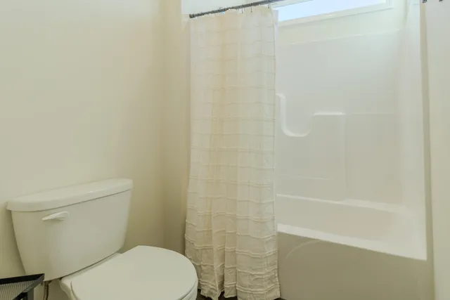 a white toilet sitting next to a shower