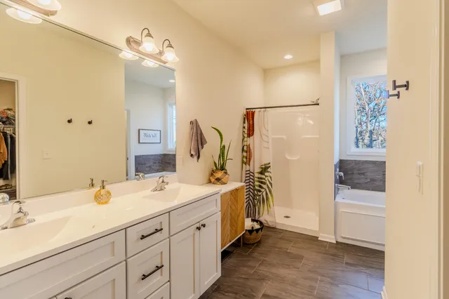 a spacious bathroom with a double vanity sink a mirror and shower