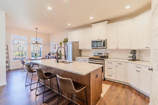 a kitchen with stainless steel appliances a stove a sink a stove a table and chairs