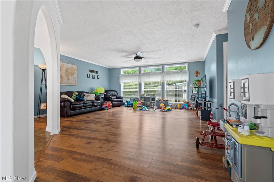 82 Patterson Ridge Road Rockport, WV 26169 - Photo 23 of 46 Living room featuring a textured ceiling, ceiling fan, dark hardwood / wood-style floors, a wall of windows, and ornamental molding