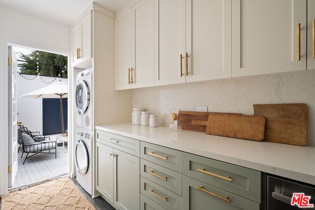 a utility room with stainless steel appliances white cabinets and a sink