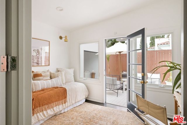 a bedroom with a balcony a bed and a dresser next to a window
