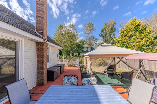 a view of a patio with couches table and chairs under an umbrella with wooden floor