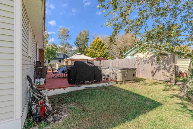 a view of a backyard with table and chairs potted plants and a large tree