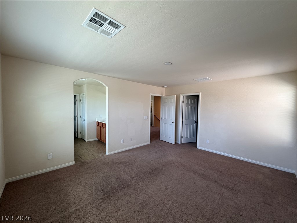 442 White Heart Road Las Vegas, NV 89148 - Photo 14 of 25 A classic archway leads to the adjacent master bathroom in this carpeted bedroom suite.