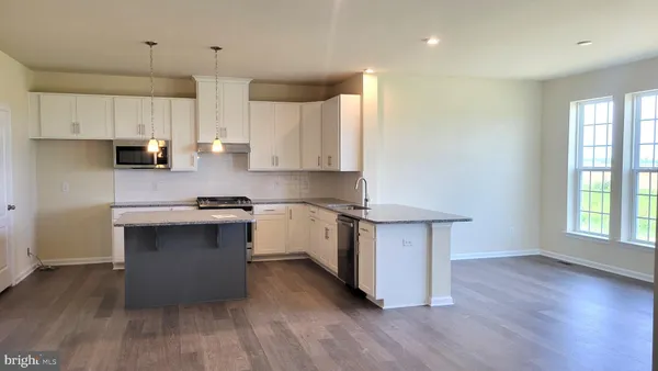 a kitchen with kitchen island granite countertop a sink cabinets and wooden floor