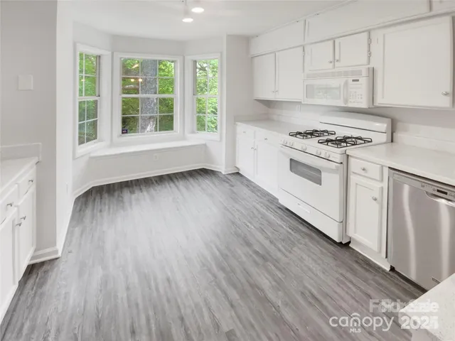 a kitchen with granite countertop white cabinets and white appliances
