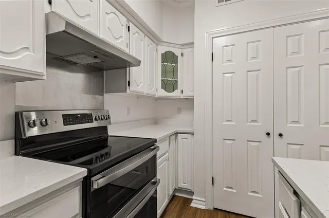 a kitchen with stainless steel appliances granite countertop white cabinets and a stove