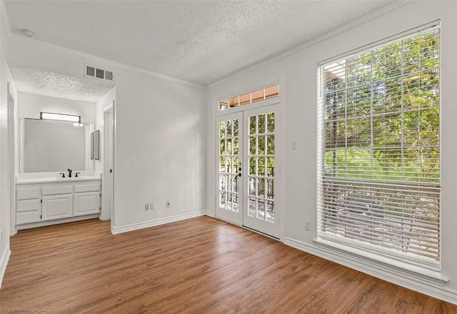 a view of an empty room with window and wooden floor