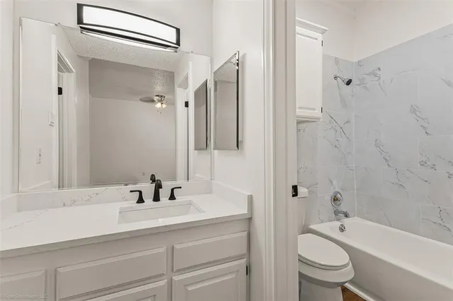 a bathroom with a bathtub shower sink vanity mirror and toilet