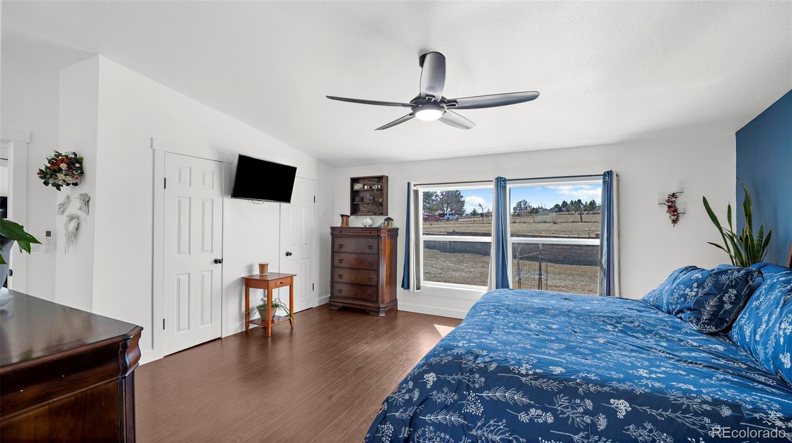 12340 Smith Road Peyton, CO 80831 - Photo 23 of 49 a spacious bedroom with a bed and a flat screen television