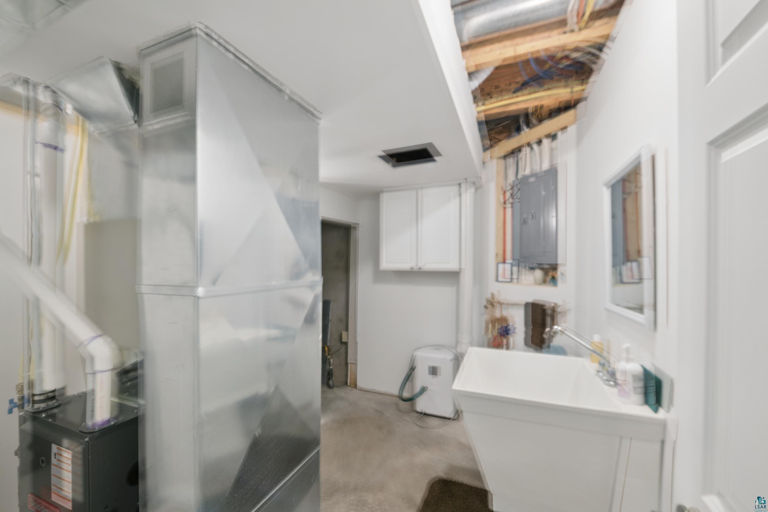 34590 Bay View Road, Unit 801 Bayfield, WI 54814 - Photo 26 of 36 Utility room featuring a laundry sink with a wall-mounted faucet, white cabinetry, and exposed ceiling joists
