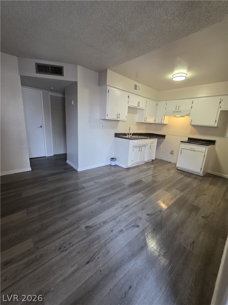 1075 East Desert Inn Road, Unit 5 Las Vegas, NV 89109 - Photo 5 of 12 A well-lit kitchen with sleek white cabinetry and durable wood-look flooring.