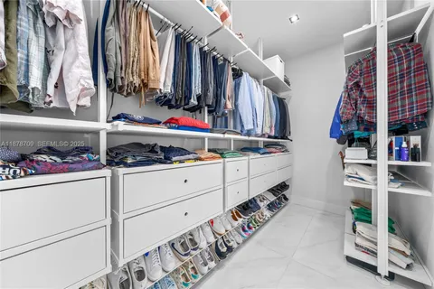 a view of walk in closet with clothes and shoes