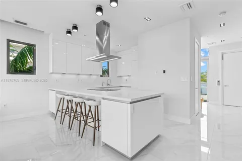 a kitchen with stainless steel appliances kitchen island a table chairs in it and white cabinets