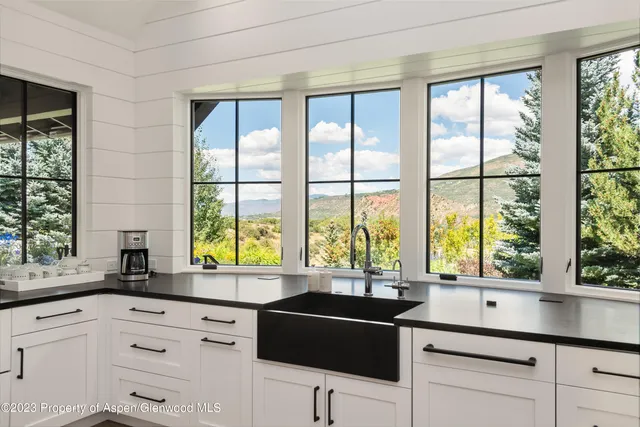 a view of a patio with couches table and chairs under an umbrella
