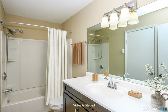 a bathroom with a sink vanity granite tub shower and a mirror