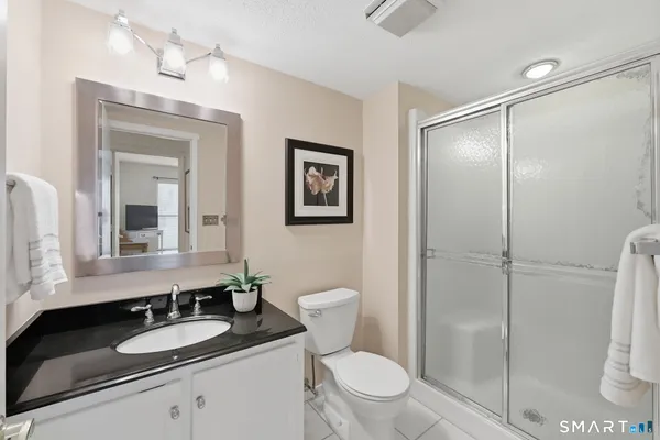 a bathroom with a granite countertop sink toilet and shower