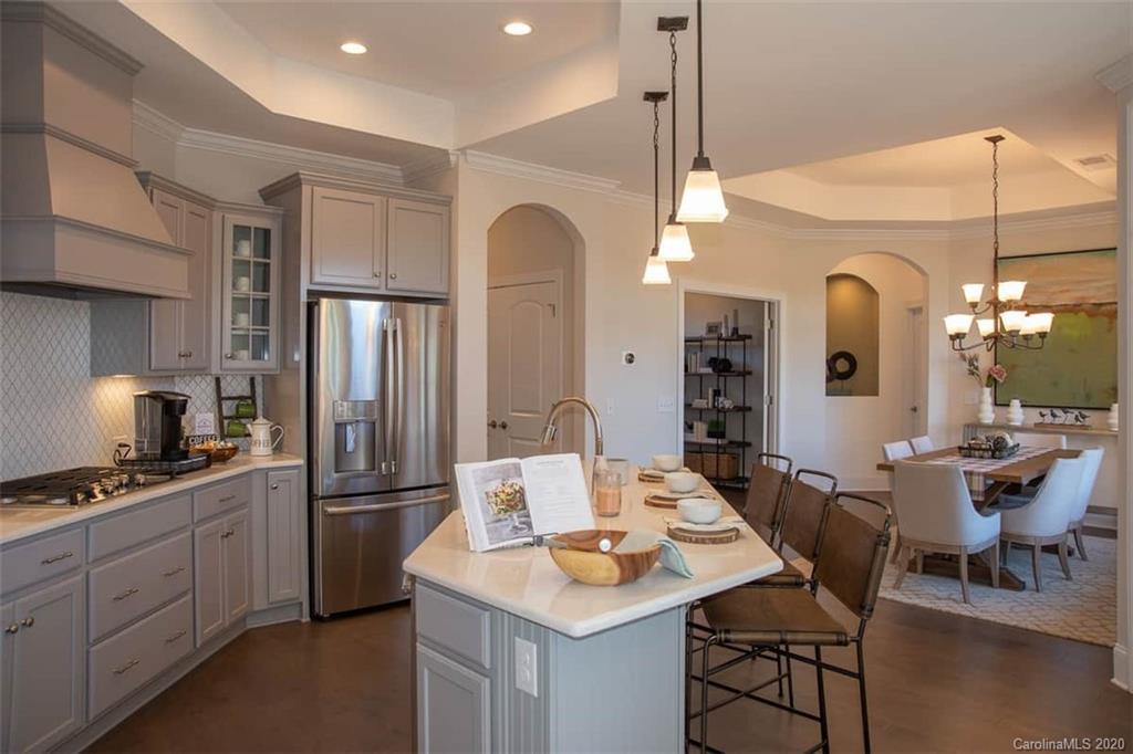 3002 Portico Place, Unit 38 Tega Cay, SC 29708 - Photo 15 of 38 a kitchen with stainless steel appliances kitchen island granite countertop a dining table chairs and a refrigerator